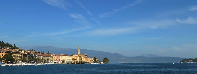 Trip Frankreich beliebte Urlaubsziele am Gardasee -  Mit einer Fläche von 370 km² ist der Gardasee der größte See Italiens. Es liegt am Fuße der Alpen und erstreckt sich über drei Staaten: Lombardei, Venetien und Trentino. Die maximale Tiefe des Sees beträgt 346 m, er hat eine längliche Form und sein nördliches Ende ist sehr schmal. Dort ist der See von den Bergen der Gruppo di Baldo umgeben. Du trittst aus deinem gemütlichen Hotelzimmer und es begrüßt dich die warme italienische Sonne. Du blickst auf den atemberaubenden Gardasee, der in zahlreichen Blautönen schimmert - von tiefem Dunkelblau bis zu funkelndem Türkis. Majestätische Berge umgeben dich, während die Brise sanft deine Haut streichelt und der Duft von blühenden Zitronenbäumen deine Nase kitzelt. Du schlenderst die malerischen, engen Gassen entlang, vorbei an farbenfrohen, blumengeschmückten Häusern. Vereinzelt unterbricht das fröhliche Lachen der Einheimischen die friedvolle Stille. Du fühlst dich wie in einem Traum, der nicht enden will. Jeder Schritt führt dich zu neuen Entdeckungen und Abenteuern. Du probierst die köstliche italienische Küche mit ihren frischen Zutaten und verführerischen Aromen. Die Sonne geht langsam unter und taucht den Himmel in ein leuchtendes Orange-rot - ein spektakulärer Anblick.
